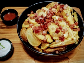Porção de batata rústica com cheddar e bacon picado
