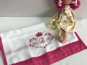 fralda para bebê personalizada com a inicial da criança acompanhada com uma boneca de pano.