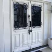 Porta clássica em madeira nobre com pintura laca branca e grades e pichados em ferro forjado.