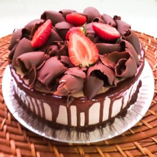 Bolo trufado preto, decorado com morangos e raspas de chocolate.