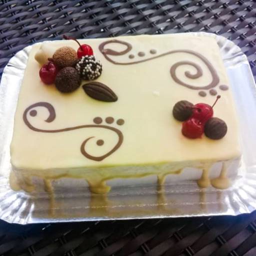 Bolo trufado preto e branco, coberto com chocolate branco e decorado com trufas, bombons e cerejas.