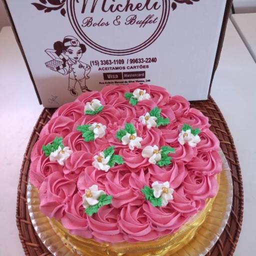 Bolo com borda dourada decorado com rosetas de chantilly.